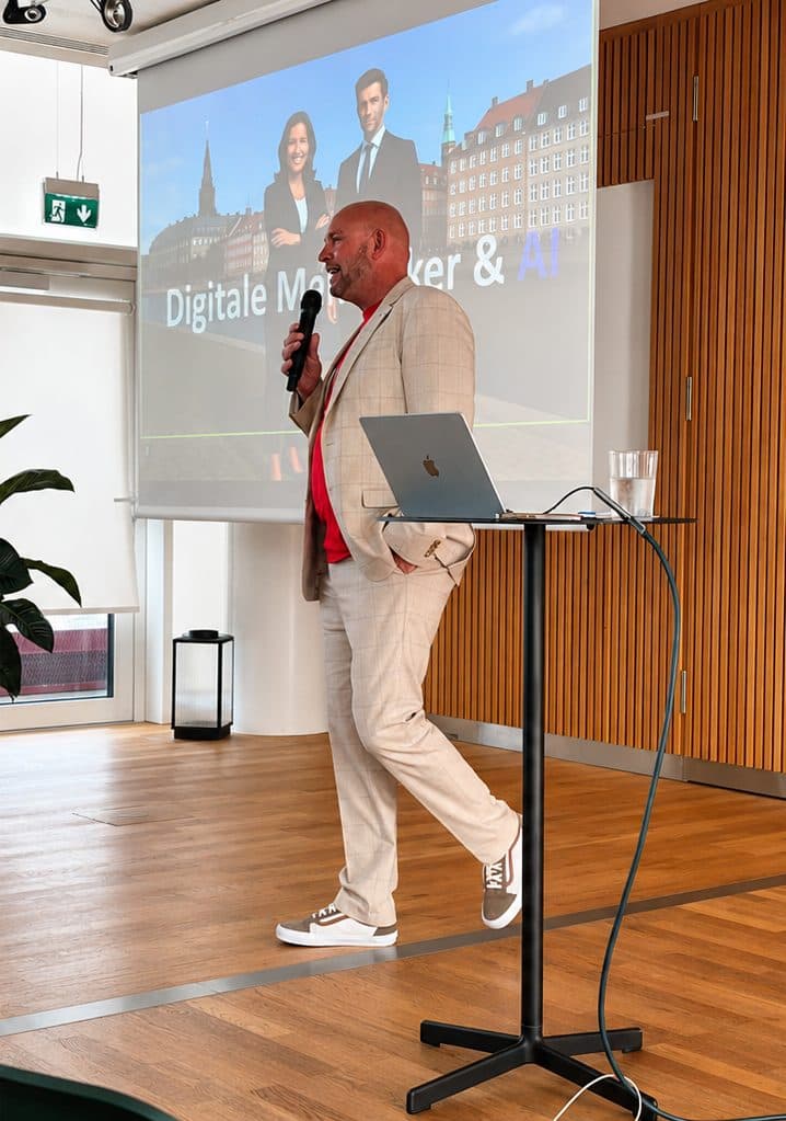 AI Event, Copenhagen, 2025: a speaker with a microphone beside a screen showing a slide in Danish